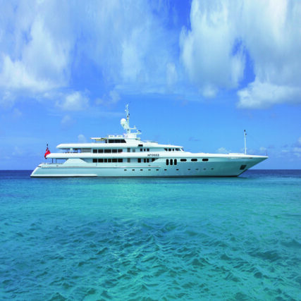 Luxury white yacht sailing on calm turquoise ocean under a partly cloudy sky.
